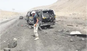  ?? (Reuters) ?? A SOLDIER TALKS on a mobile phone as he stands at the site of a suicide car bomb attack at a military checkpoint near the government-held port city of Mukalla, Yemen, yesterday.