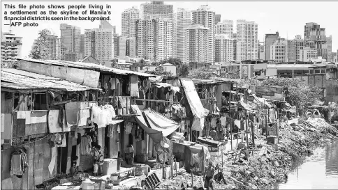  ?? — AFP photo ?? This file photo shows people living in a settlement as the skyline of Manila’s financial district is seen in the background.