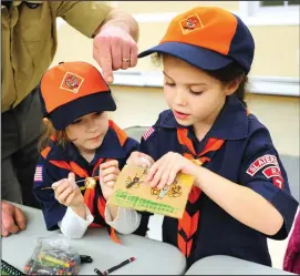  ?? Ernest A Brown photos ?? At top, Josh Thibeault, incoming Scout Master, left, assists Scouts Maddie Silva and Susie Casper, both 9, as they construct their Pinewood Derby cars Tuesday. Tiger Scouts Betty Stapleton, left, and Caroline Boulay, both 6, work on a crafts during the monthly meeting of Cub Scouts Pack 7 Slatersvil­le at Scouters Hall.