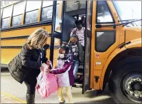  ?? NATE GUIDRY — PITTSBURGH POST-GAZETTE VIA AP ?? Laura Del Rosso, a math teacher at Wilkins Elementary STEAM Academy, assists students off the bus as they arrive for the first day of Woodland Hills School District’s return to in-person schooling since it was suspended a year ago due to the COVID-19 pandemic, Monday, March 29, 2021, in Wilkins Township, Penn.