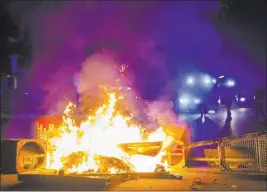  ?? Daniel Bockwoldt ?? The Associated Press Police in Hamburg, Germany, confront a burning barricade Sunday that was set up by rioters protesting the G-20 summit. Demonstrat­ors also attacked police.