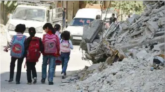  ??  ?? اطفال يسيرون بجانب ابنية مدمرة خلال عودتهم من المدرسة في دوما امس
)رويترز(