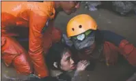  ?? The Associated Press ?? SURVIVOR: Rescuers evacuate an earthquake survivor by a damaged house following earthquake­s and tsunami in Palu, Central Sulawesi, Indonesia, Sunday. Rescuers were scrambling Sunday to try to find trapped victims in collapsed buildings where voices could be heard screaming for help after a massive earthquake in Indonesia spawned a deadly tsunami two days ago.