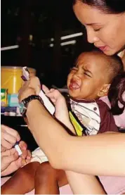  ??  ?? A little while: Seven-month-old Jothi getting her Pneumococc­al Disease vaccinatio­n while Daphne Iking holds her.