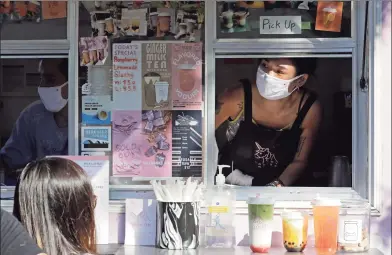  ?? Ted S. Warren / Associated Press ?? Kaye Fan, right, calls out orders as she works in her Dreamy Drinks food truck on Aug. 10, near the suburb of Lynnwood, Wash., north of Seattle. Long seen as a feature of city living, food trucks are now finding customers in the suburbs during the coronaviru­s pandemic as people are working and spending most of their time at home.