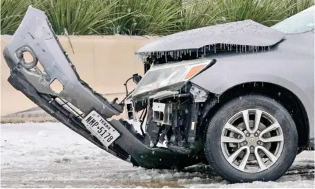  ?? AP PHOTO/TONY GUTIERREZ ?? A wrecked car with ice build up sits on U.S. Highway 75 as emergency workers nearby work to remove it from the highway Wednesday in Dallas.