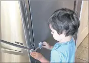  ?? MARY SETHNA — VIA AP ?? Imran Sethna, 3, examines a child safety latch on the refrigerat­or door in Broomfield, Colo.