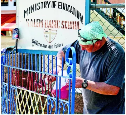  ?? PHOTOS BY CARL GILCHRIST ?? A volunteer from Sober Vacations Internatio­nal paints a gate at Salem Basic School.