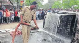  ?? HT FILE ?? A policeman douses fire on the car of Alimuddin, who was lynched by an angry mob. Pictures on social media showed people hitting him, meat pieces strewn on the road and his car up in flames.
