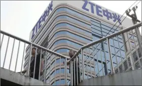  ??  ?? In this May 8 file photo, Chinese men pass by a ZTE building in Beijing, China. A bipartisan effort in Congress clamp down on China telecom giant ZTE is being stripped from the final version of a big defense bill, aides said July 20, essentiall­y...