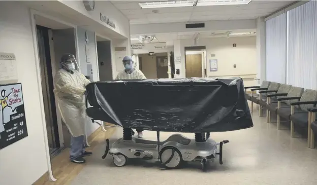  ??  ?? 0 Hospital staff enter a lift with the body of a Covid-19 victim on a gurney at St Jude Medical Center in Fullerton, California