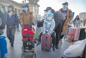  ?? Mark Schiefelbe­in, The Associated Press ?? Travelers wear face masks as they walk outside of the Beijing Railway Station on Monday as the country deals with an outbreak of coronaviru­s.