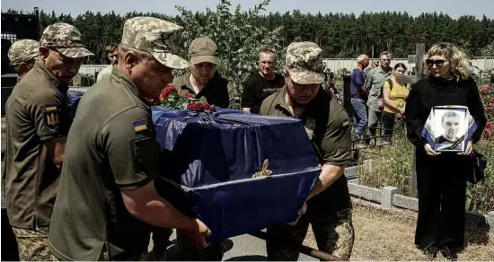  ?? Mauricio Lima/The New York Times ?? Soldados ucranianos carregam caixão de combatente morto por bombardeio russo, durante funeral em Butcha