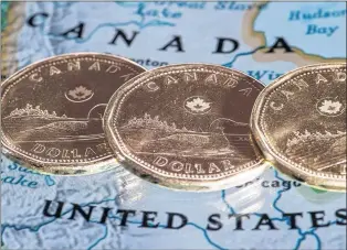  ?? CP FILE PHOTO ?? Canadian dollar coins are displayed on a map along the border of Canada and the United States of America.