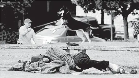  ?? TED S. WARREN/AP ?? A man sleeps in May at a Seattle park. Some 400 homeless people in Washington state’s biggest city have been diagnosed with the coronaviru­s.