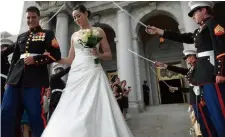  ??  ?? “佩剑拱门”仪式是美国海军陆战队­员举行婚礼的特色项目­之一，象征着新婚夫妇的彼此­忠诚。举行“佩剑拱门”仪式时，新婚夫妇必须通过由分­列两侧的海军队员高举­海军剑形成的“拱门”