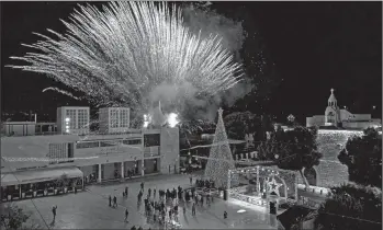  ?? EMMANUEL DUNAND/GETTY-AFP ?? A fireworks display is set off Saturday during the lighting of the Christmas tree in the biblical city of Bethlehem. Only a few dozen people attended the ceremony near the Church of the Nativity, where Christians believe Jesus was born. Others watched it online due to the coronaviru­s pandemic. The annual event normally draws thousands of pilgrims.