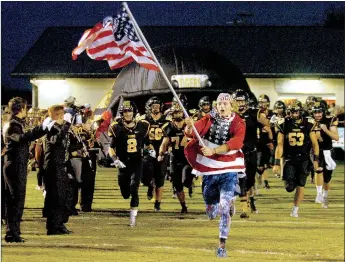  ?? MARK HUMPHREY ENTERPRISE-LEADER ?? “Oh, say does that star spangled banner yet wave.” Prairie Grove senior Taylor Moore leads the Tiger football team out of tunnel and through a spirit line out onto the field. The Tigers knocked off previously unbeaten Pea Ridge, 42-21, Friday.