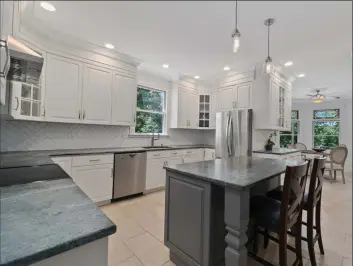  ?? Photos by Coldwell Banker Residentia­l Brokerage ?? Above: The newly renovated kitchen at 105 Honeysuckl­e Lane in Easton features soap stone counter tops, extensive cabinetry, a custom island and new stainless- steel appliances. Below: The breakfast room has stained glass transoms and views of the lush landscape. The home is listed for $ 769,000.