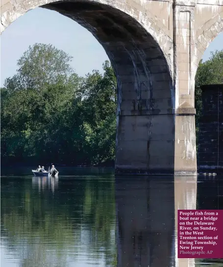  ?? Photograph: AP ?? People fish from a boat near a bridge on the Delaware River, on Sunday, in the West Trenton section of Ewing Township, New Jersey