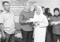  ??  ?? Hasidah (second left) presents the incentive to a student.