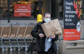  ?? ELAINE THOMPSON ?? In this Monday, March 30, 2020, photo, a shopper leaves a grocery story with food packed in a paper bag, where the dime-per-bag fee has been waved during the coronaviru­s outbreak, in Seattle. Just weeks earlier, cities and even states across the U.S. were busy banning straws, limiting takeout containers and mandating that shoppers bring reusable bags or pay a small fee. Grocery clerks are nervous that the virus could linger on reusable fabric bags and their unions are backing them up with demands to end plastic bag fees and suspend bag bans. The plastics industry has seized the moment, lobbying to overturn existing bans on single-use plastics.