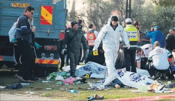  ?? AHMAD GHARABLI / AFP ?? Fuerzas de seguridad y equipos médicos junto a los cadáveres de algunos de los soldados víctimas del atentado de ayer en Jerusalén