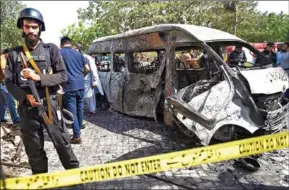  ?? AFP ?? Police inspect a site around damaged vehicles following a suicide bombing near the Confucious Institute affiliated with the Karachi University, in Karachi on Tuesday.