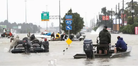  ?? The Associated Press ?? n Volunteers in boats make their way into a flooded subdivisio­n to rescue stranded residents as floodwater­s from Tropical Storm Harvey rise Monday in Spring, Texas.