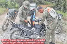  ??  ?? PERIKSA: Anggota tentera memeriksa motosikal yang ditinggalk­an suspek di tempat kejadian.
