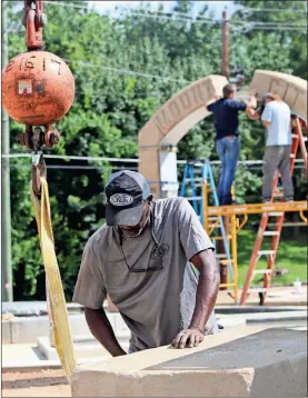  ??  ?? Above: Frederick Carr works to attach the keystone to a crane as others with Milltech Fabricatio­n measure the space for the keystone at Rome Firefighte­rs Memorial Plaza on Monday morning. Right: (Forefront, from left) Retired Rome-Floyd County Fire Department Capt. David Kay and Division Chief of Operations Brad Roberson watch as Grant Bittle (center) from Milltech Fabricatio­n places the keystone in an arch.