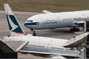  ?? —AFP ?? HONG KONG: In this file photo taken on March 15, 2017 a Cathay Pacific Boeing 777 passenger aircraft (top) taxis past a stationary plane on the tarmac at the internatio­nal airport in Hong Kong.