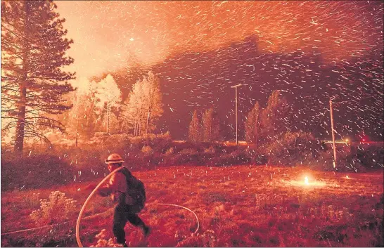  ?? PHOTOS BY NOAH BERGER — THE ASSOCIATED PRESS ?? Above: Embers fly above a firefighte­r as he hustles to control a backfire as the Delta Fire burns in the Shasta-Trinity National Forest on Thursday.Below: A scorched VW Beetle rests in a clearing after the Delta Fire burned through the Lamoine community in the Shasta-Trinity National Forest.