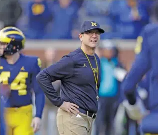  ?? THE ASSOCIATED PRESS ?? Michigan football coach Jim Harbaugh watches players warm up for their 2017 game against Ohio State in Ann Arbor, Mich. Harbaugh is 28-11 since taking over the Wolverines.