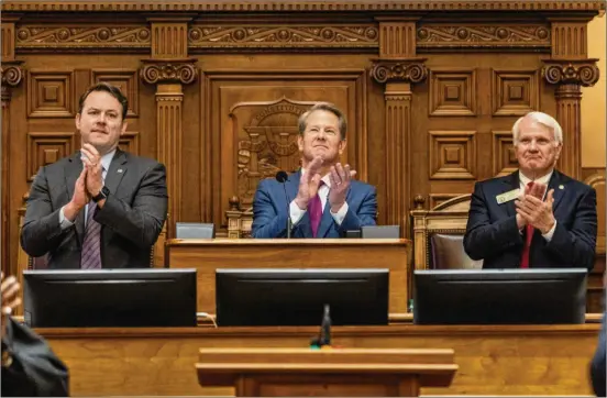  ?? ARVIN TEMKAR/ARVIN.TEMKAR@AJC.COM ?? Gov. Brian Kemp, flanked by Lt. Gov. Burt Jones (left) and House Speaker Jon Burns, joins in the applause from members of the Georgia Legislatur­e on Wednesday, when the governor laid out his agenda in his State of the State address at the Capitol.