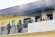  ?? MIKE STOCKER/SUN SENTINEL ?? Firefighte­rs and police make entry to an apartment on the third floor of a complex on Northeast 48th Street.