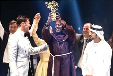  ??  ?? Tabichi (centre) holding up the Global Teacher Prize (GTP) trophy after winning the US$1 million award during an official ceremony in Dubai presented by Australian actor Hugh Jackman (left) and attended by the Dubai Crown Prince Hamdan bin Mohammed Al-Maktoum (right). — AFP photo