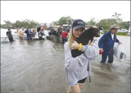  ?? AP PHOTO ?? Mikhail Bachynsky hugs her dog Lily after they were rescued from their home in the Friendswoo­d area of Houston. Neighbours with boats are using their personal boats to rescue people stranded by flooding.