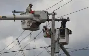  ?? (Special to The Commercial/Richard Ledbetter) ?? Entergy linemen work to replace damaged transmissi­on lines and restore electric service on Russell Street in Fordyce to some of the 181,000 customers left in the dark by the major ice storm.