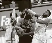  ??  ?? The Spurs’ Keldon Johnson grabs a rebound between the Rockets’ Christian Wood, left, and David Nwaba.