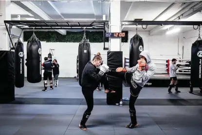  ?? Photos by Mary Turner / New York Times ?? Participan­ts spar during a muay thai class at Fightzone in London last week. After a year marked by isolation, loneliness and violence in London, many self-defense and martial arts gyms say they are seeing more interest from women.