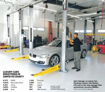  ?? Ian's Garage co-owner Ian Clemmer lowers the Rotary Lift unit in his new garage that exclusivel­y services BMWs. TEYA VITU / THE NEW MEXICAN ??