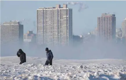  ??  ?? FRÍO. Dos hombres caminan por una avenida de Chicago, pese a la baja temperatur­a que se registra en esa ciudad. (AFP)