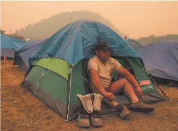  ?? CP photo ?? Firefighte­r Raymundo Rosales of Mexico, sits outside his tent at a camp of wildfire firefighte­rs and staff at an outdoor sports field in Fraser Lake on Aug. 2018.