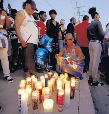  ?? Francine Orr Los Angeles Times ?? DONNA STEWART lights a candle during a vigil in Palmdale for Armando Garcia-Muro, who was shot and killed by a stray bullet fired by a deputy in what was called an “extremely, extremely unfortunat­e incident.”