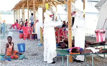  ??  ?? Health workers wearing personal protective equipment assist an Ebola patient at the Kenama treatment centre run by the Red Cross Society. — AFP photo