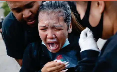  ??  ?? A woman is helped after being hit with pepper spray after curfew on Sunday