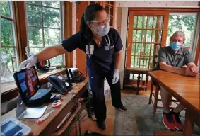  ?? (AP/Elise Amendola) ?? Nurse practition­er Sadie Paez picks up a tablet to set up a telehealth session for William Merry, who was recovering from pneumonia in July at his home in Ipswich, Mass.