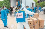  ?? ?? A worker disinfects boxes of food being distribute­d by local government to residents in a compound during a COVID-19 lockdown in Shanghai on Friday. The city is easing rules that confined most of its 25 million people to their homes, but most of its businesses are still closed.