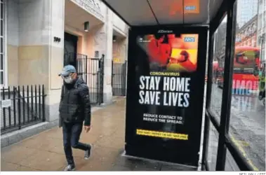  ?? NEIL HALL / EFE ?? Un hombre con mascarilla pasa junto a un cartel que advierte del coronaviru­s, ayer en Londres.